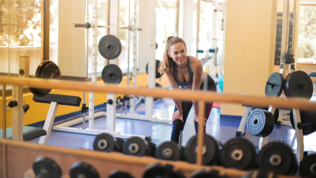 Fit woman in a gym with weights, showcasing strength and fitness lifestyle.